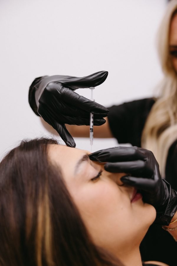 Elizabeth Hurley, RN BSN CANS, performing a Botox treatment at Privé Aesthetics — wearing the Privé branded scrub, mapping placement on a client