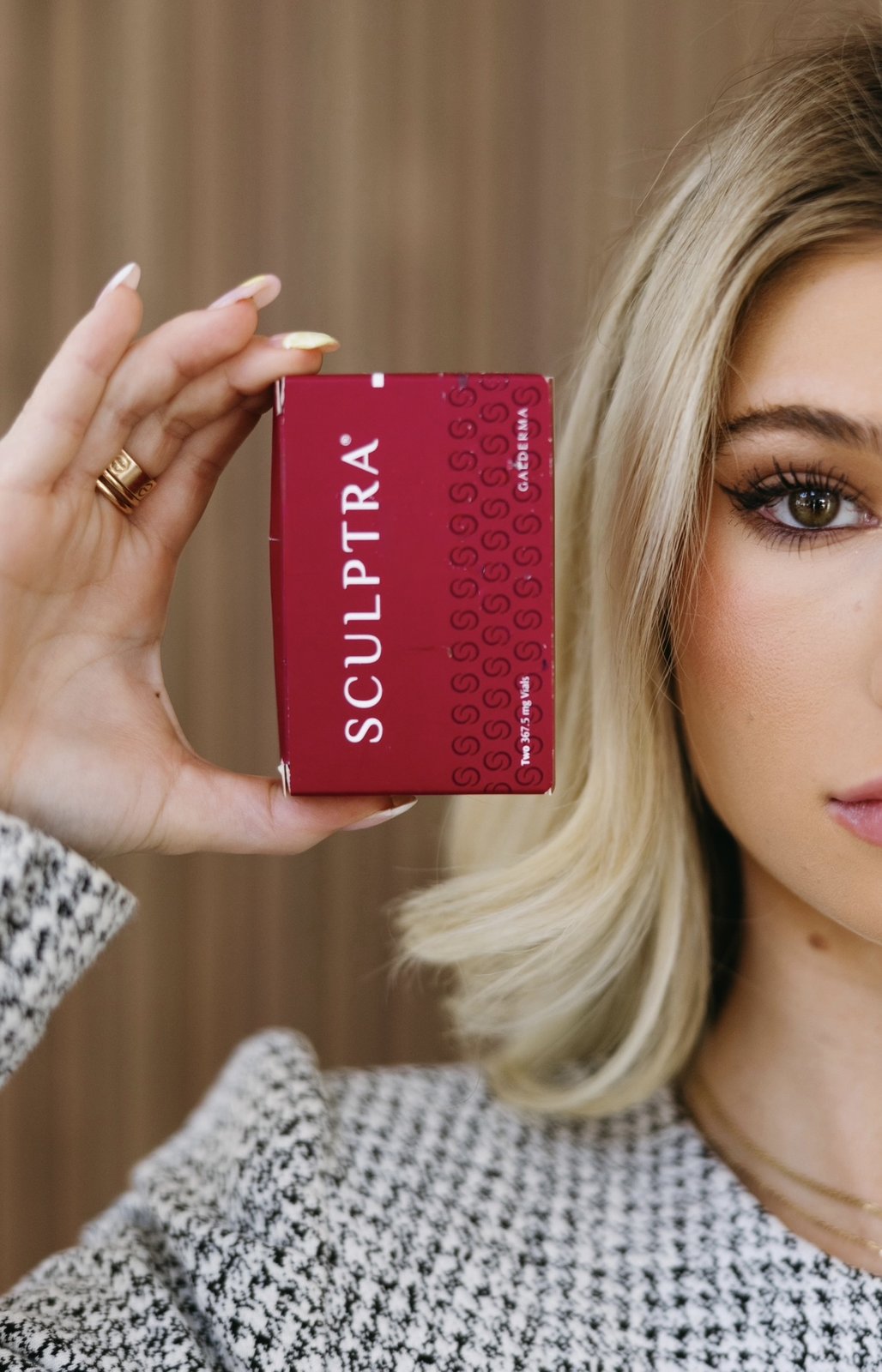 A Privé client holding a Sculptra (Galderma) box at the Hillcrest studio in Dallas — the FDA-approved poly-L-lactic acid biostimulator used for gradual collagen-driven facial restoration